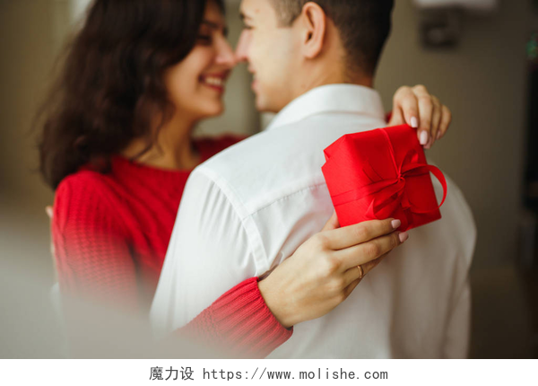 一个妻子拿着礼物抱着丈夫幸福的一对，抱着礼物。 手拿着礼物的一对快乐的夫妇彼此享受着. 情人节庆祝的概念。 关系、惊喜和爱情概念.